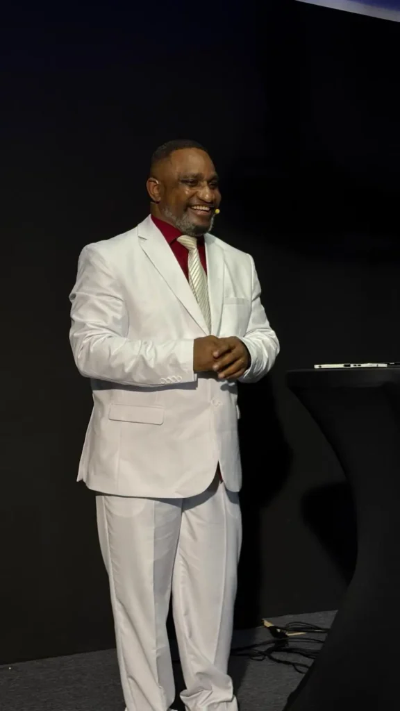 Dr. Mishael Carson speaking on stage in a white suit